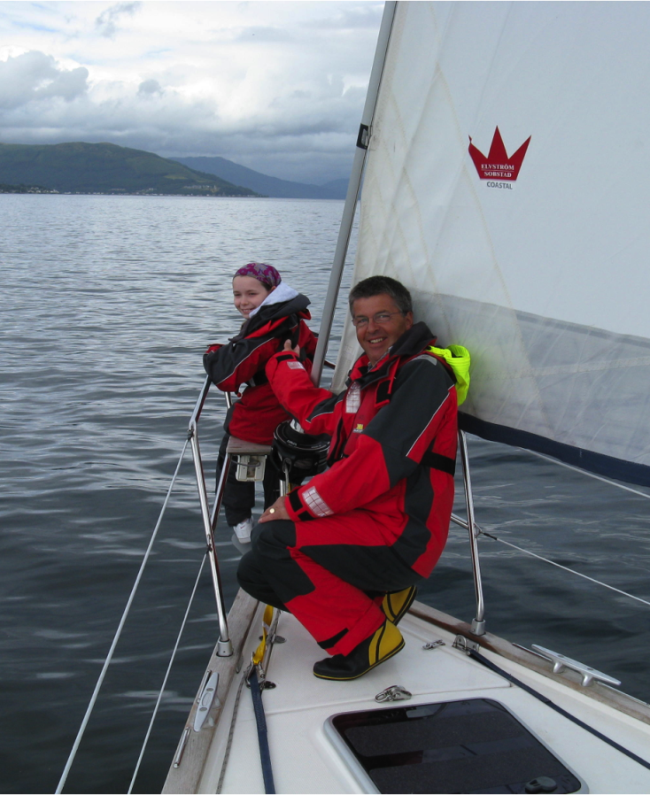 Young client at bow of yacht with volunteer crew