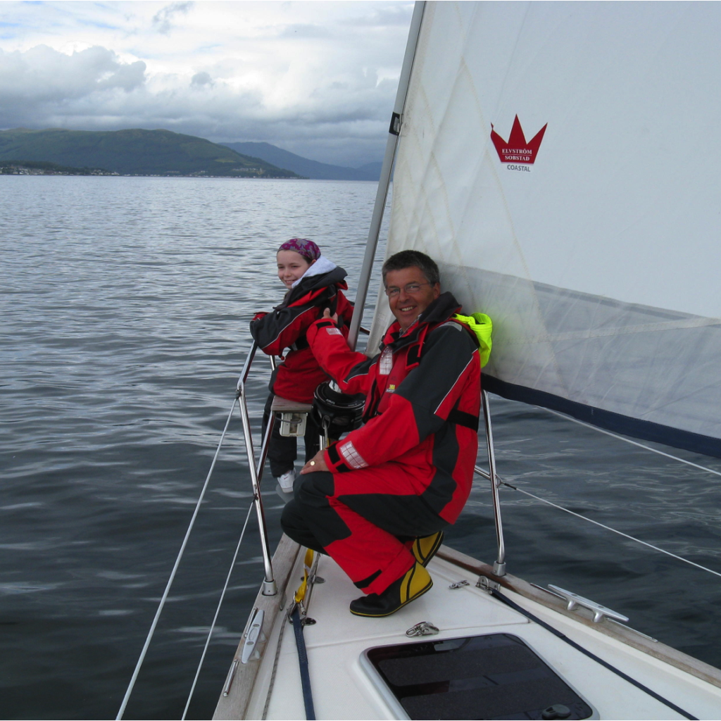 Young client at bow of yacht with volunteer crew